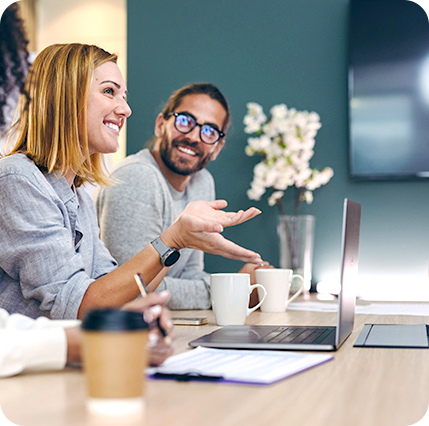 Foto Mann und Frau an einem Besprechungstisch mit Laptop