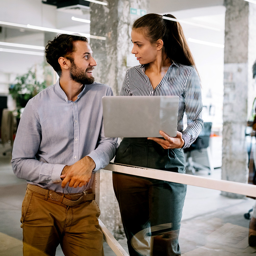Bild Büroszene wobei sich ein Mann und Frau mit Laptop anschauen