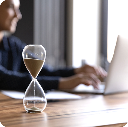 Bild Sanduhr im Hintergrund arbeitet Person am Laptop