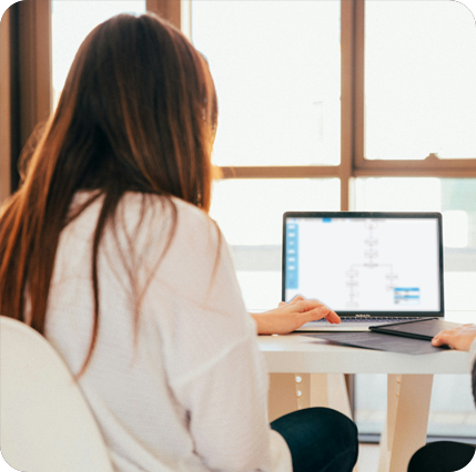 Foto Frau sitzt vor dem Laptop wo ein Workflow zu sehen ist